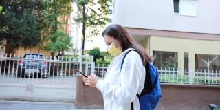 忧心忡忡的妇女戴着防护口罩，用智能手机走在街上