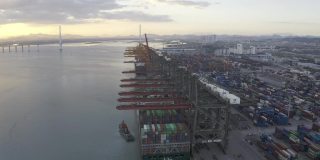 夕阳下，几艘大型货轮停在港口装卸集装箱。