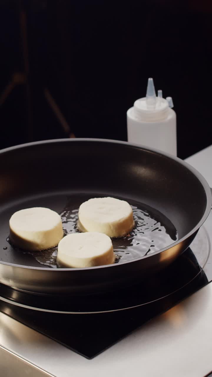 近距离拍摄金黄的松软干酪在煎锅中旋转煎炸。俄罗斯，乌克兰，白俄罗斯的美食。准备健康美味的早餐奶酪蛋糕