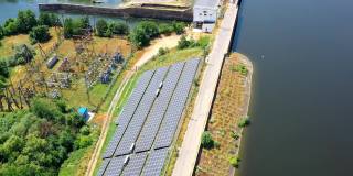 太阳能电站附近的河在阳光。光伏太阳能电池在现代太阳能农场从太阳中产生清洁能源。鸟瞰图。