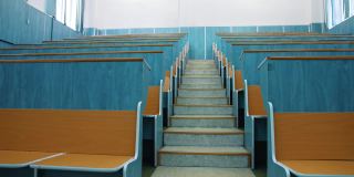空的礼堂。会议厅两排桌子之间的楼梯。美丽的课堂，学习没有学生。大学的教室里有木制的课桌。