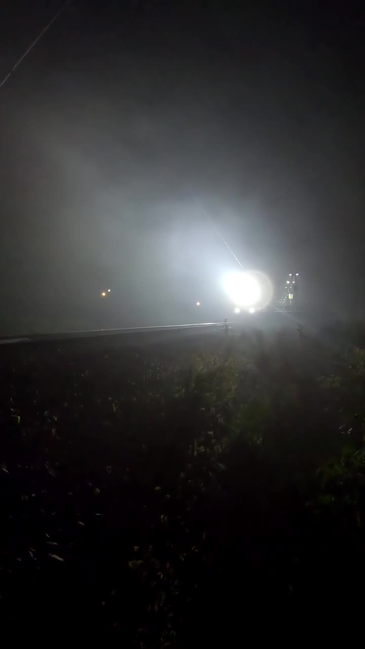 火车探照灯在夜雾中闪烁。火车给标志-垂直镜头
