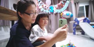 在家里举行的生日聚会上，母亲和儿子正在用手机视频通话