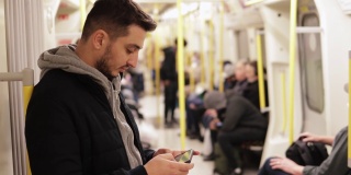 年轻人在地铁里打电话，用智能手机玩游戏，用手机发短信，用手机浏览社交媒体，用一只手玩游戏，戴着耳机听音乐