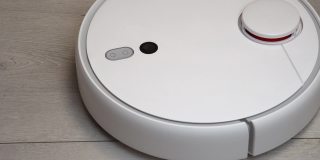 客厅里的机器人吸尘器。现代真空机器人在家里自动清洁。机器人吸尘器清洁木地板