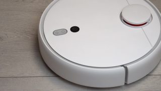 客厅里的机器人吸尘器。现代真空机器人在家里自动清洁。机器人吸尘器清洁木地板视频素材模板下载