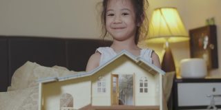 可爱的5岁亚洲女孩是玩具娃娃房，晚上在床上微笑和幸福显示学习和创造力的概念，通过在家的休闲活动。