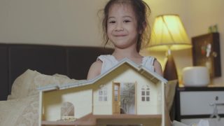 可爱的5岁亚洲女孩是玩具娃娃房，晚上在床上微笑和幸福显示学习和创造力的概念，通过在家的休闲活动。视频素材模板下载