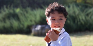 一个小男孩正在公园里吃面包