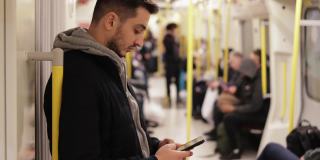 年轻人在地铁里打电话，用智能手机玩游戏，用手机发短信，用手机浏览社交媒体，用一只手玩游戏，戴着耳机听音乐