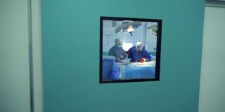 医生和护士做手术。透过窗户可以看到医院的手术过程。大流行期间的手术室。冠状病毒