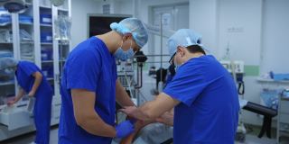 手术的腿。在现代化的手术室里，穿着蓝色制服的医学专家正在给躺在手术台上的病人做手术。