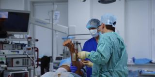 在手术室进行医疗程序医生在手术前准备好病人的腿。在现代诊所工作的医务人员。