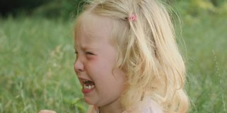 悲伤的金发小女孩在公园里哭着，眼里含着泪水