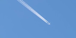 远处的喷气式客机在晴空万里的高空飞行，留下白色的烟雾和尾迹。航空运输的概念