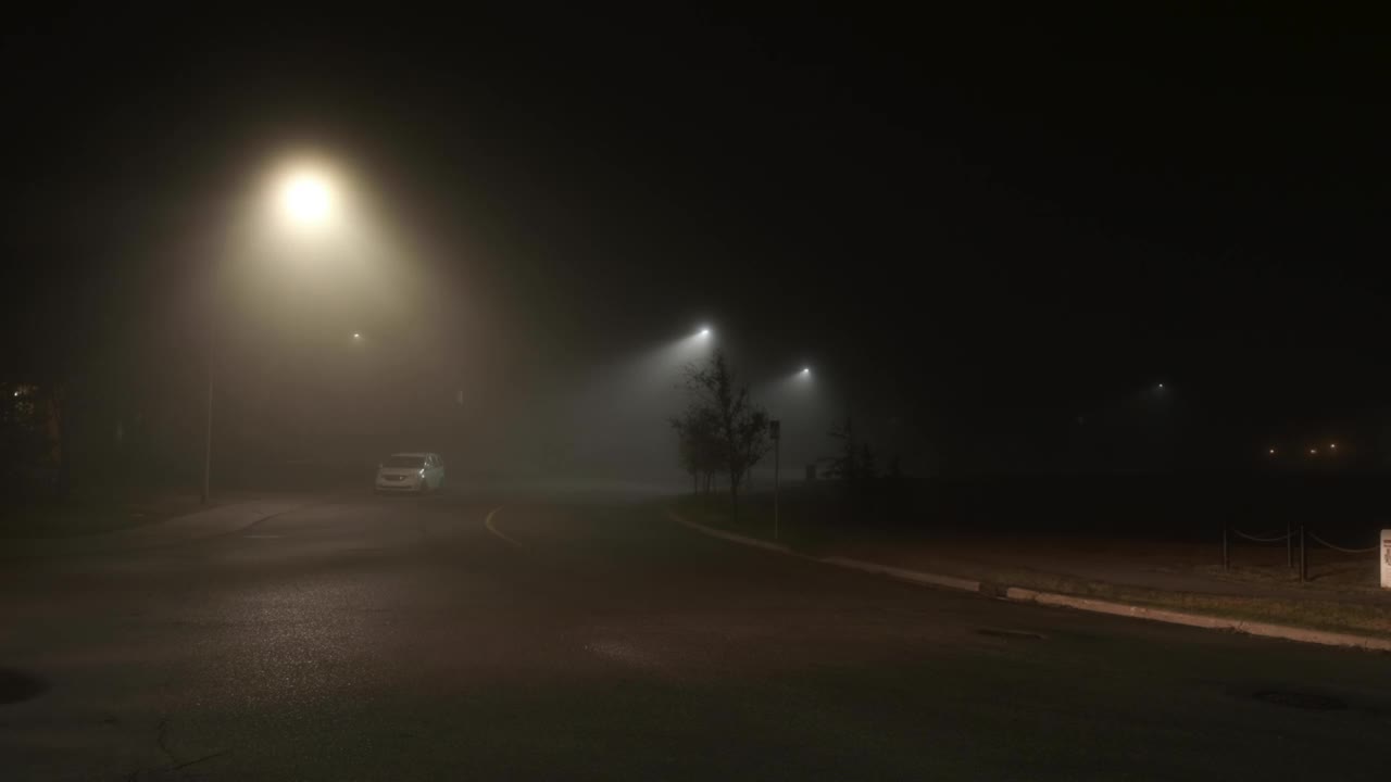 雾蒙蒙的城市街道上稀疏的夜间交通