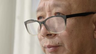窗前的一位中国老人，戴着老花镜，凝视着前方视频素材模板下载