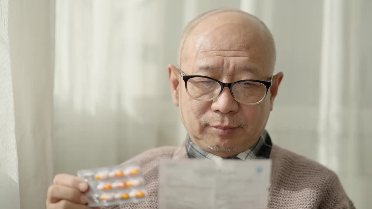 一位中国老人坐在窗边，戴着老花镜，阅读说明书