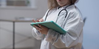 一个无法辨认的小个子穿着病号服站在医院室内平板电脑上上网。年轻的白人女性思考阅读最新的在线新闻。医学和现代技术。