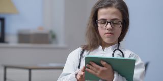 自信聪明的女医生的肖像，戴着眼镜，大拇指向上，微笑地看着相机，站在室内平板电脑。快乐的白人小人在医院摆姿势工作。