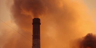 从工业烟囱中冒出的浓烟。一团团的污染物污染着大气。夜空中一股股的烟雾。日落时的污染工厂。