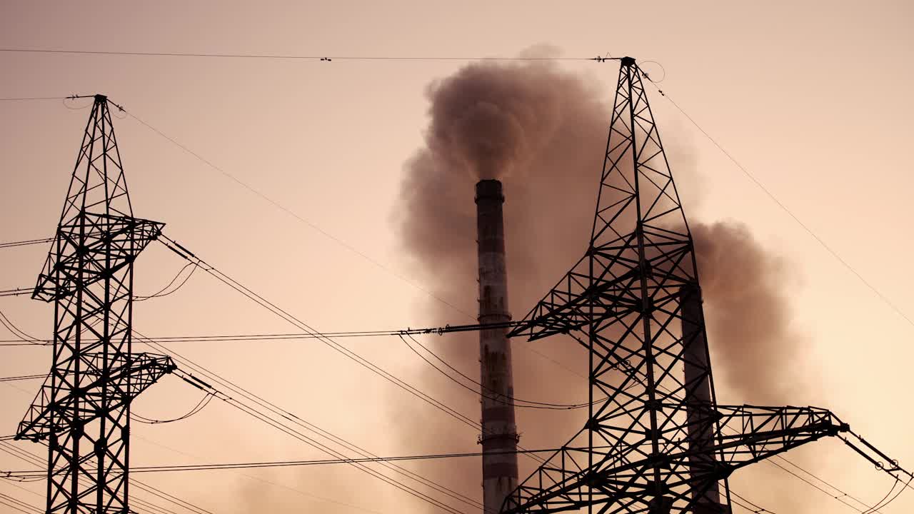输电线路旁边的工厂管道有黑烟。高管道黑烟污染大气。生产的电力。环境问题。