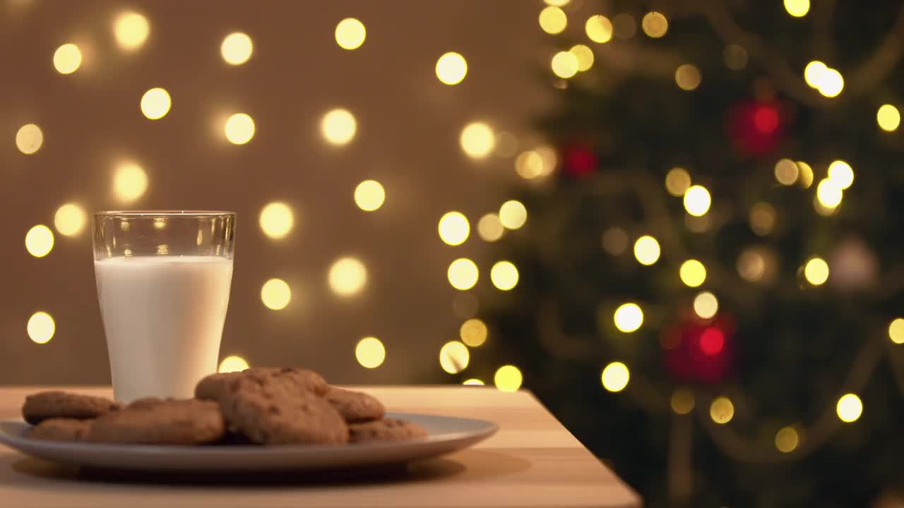 圣诞老人的手从桌子上拿起一杯牛奶，圣诞老人喝完牛奶后，把空杯子放回原处。
