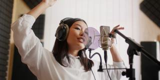 新的轨道。精力充沛的亚洲女歌手在音乐工作室录制歌曲