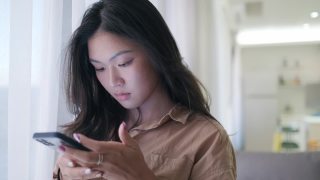 亚洲女性在家里使用智能手机视频素材模板下载