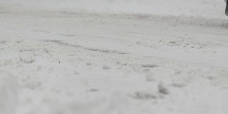 在冬天的城市里，汽车行驶在白雪覆盖的道路上。降雪。慢动作的车轮特写。轮胎面。恶劣的天气条件，交通，暴风雪。危险之旅