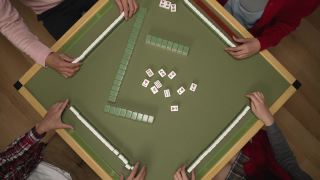 从上面看，人们的手采摘和铺在桌子上的绿色麻将牌，而玩瓷砖游戏在中国春节假期期间在家里视频素材模板下载