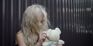一个小女孩拿着一个简单的玩具。她那乱蓬蓬的头发遮住了她的脸。