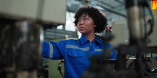女性非裔美籍机械工程师操作数控铣床的安装过程，女性技术员工作在生产金属产品的进度线