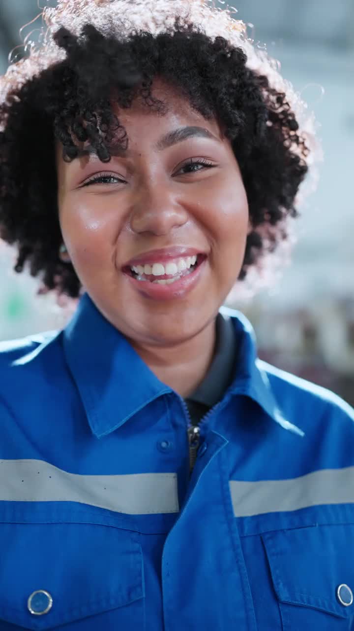 垂直拍摄肖像微笑开朗的非裔美国女技术员工程师穿着安全制服笑微笑幸福的工作环境在制造工厂的背景