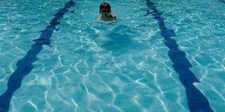 慢动作镜头的年轻混合亚洲十几岁的男孩游泳蛙泳在一个游泳池，儿童运动
