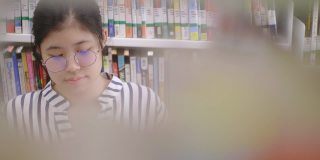 亚洲女孩坐在图书馆看书