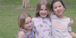 快乐的多民族混血小女孩在公园里拥抱和欢笑，积极的健康理念