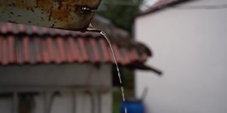 下雨的时候，雨水从一个生锈的自制水沟里流出来