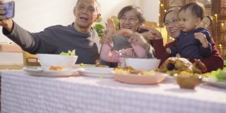 亚洲家庭用手机自拍在晚餐时，庆祝圣诞假期在公寓