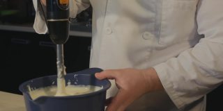 糕点师用搅拌机搅拌完奶油，将剩下的奶油轻拍在碗上，然后取出搅拌机