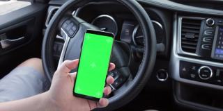 男人的手使用chromakey手机空绿色屏幕在现代汽车。模型触摸屏。滚动的智能手机显示特写。