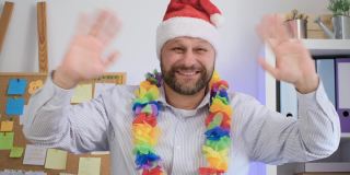 戴着圣诞帽的中年男子对着镜头微笑。圣诞节的概念视频通话。使用电脑进行在线电话直播视频会议聊天，家庭办公闭路摄像头查看。