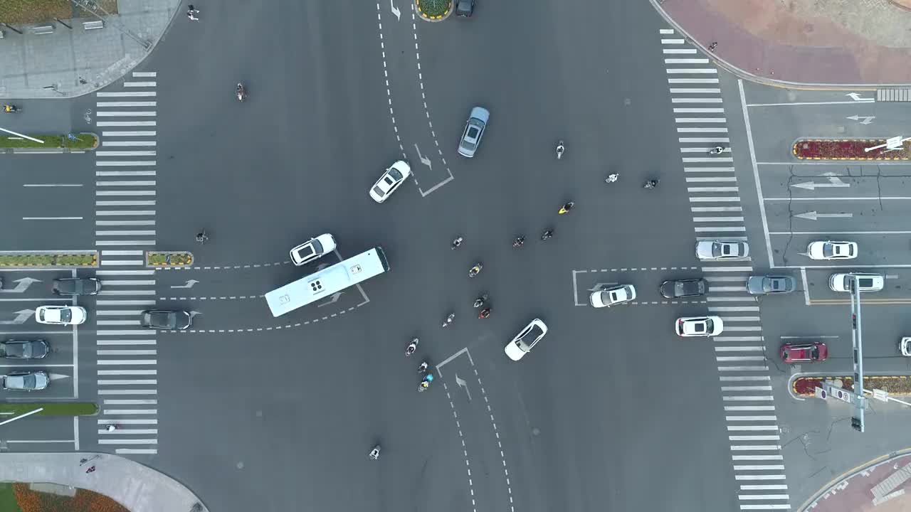 加速无人机拍摄的城市十字路口，汽车和公交车行驶在大道上。在日落时
