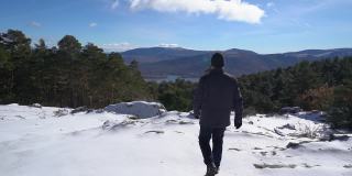 一个人走在雪山上，望着绿色的山谷。Guadarrama马德里。