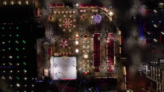 圣诞市场，鸟瞰。圣诞旋转木马，溜冰场，巨大的装饰圣诞树和摩天轮。现代城市灯火通明的圣诞集市。视频素材模板下载
