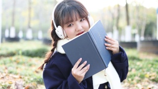 秋天，一个女人在外面听音乐看书。视频素材模板下载