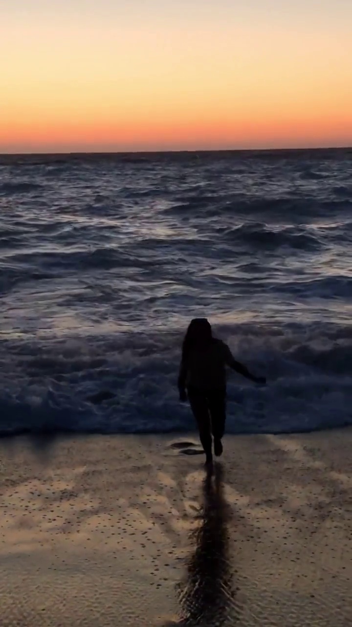年轻女子跑向海边欣赏日落美景