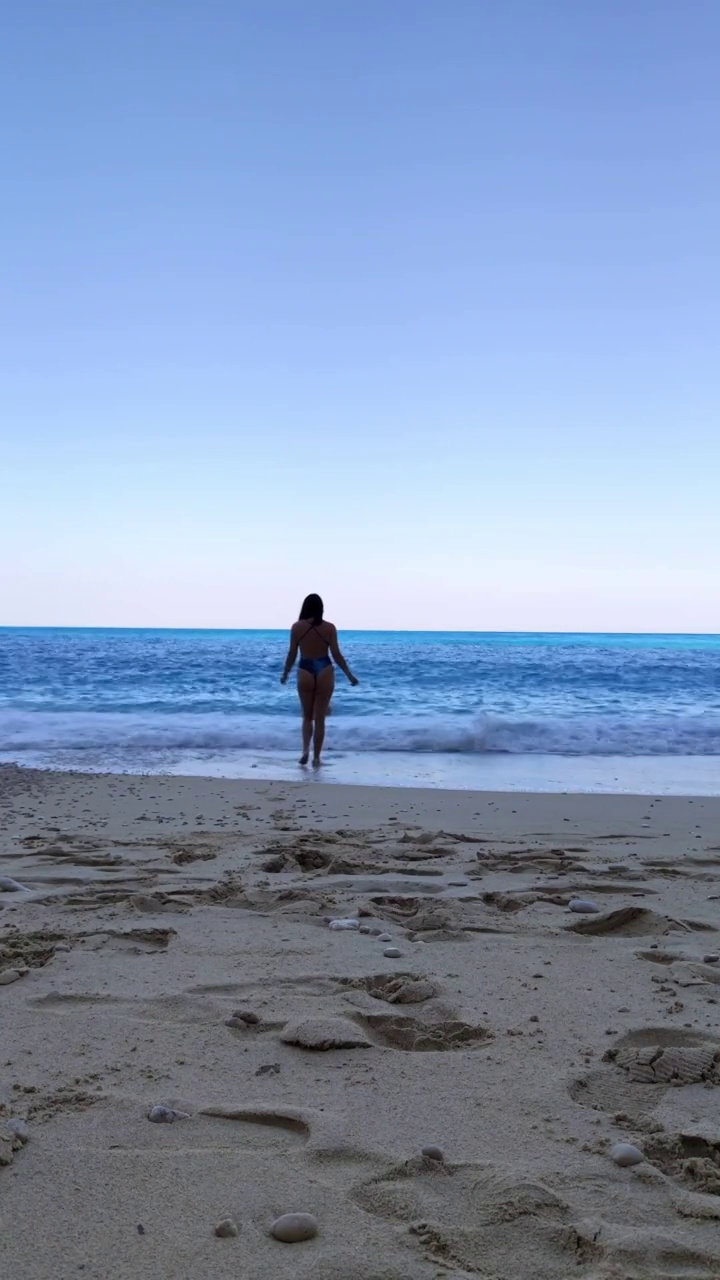 穿着蓝色泳装的女人走在海滩上