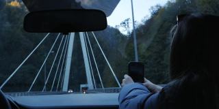 汽车在桥上。手放在方向盘和仪表盘上，白天开车过桥。一个女孩从车里拍摄道路的景色。慢动作
