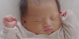 特写快乐的新生儿躺在白色的毯子上睡觉，舒适和安全。可爱的亚洲新生儿在床上睡觉和打盹。新生儿摄影理念